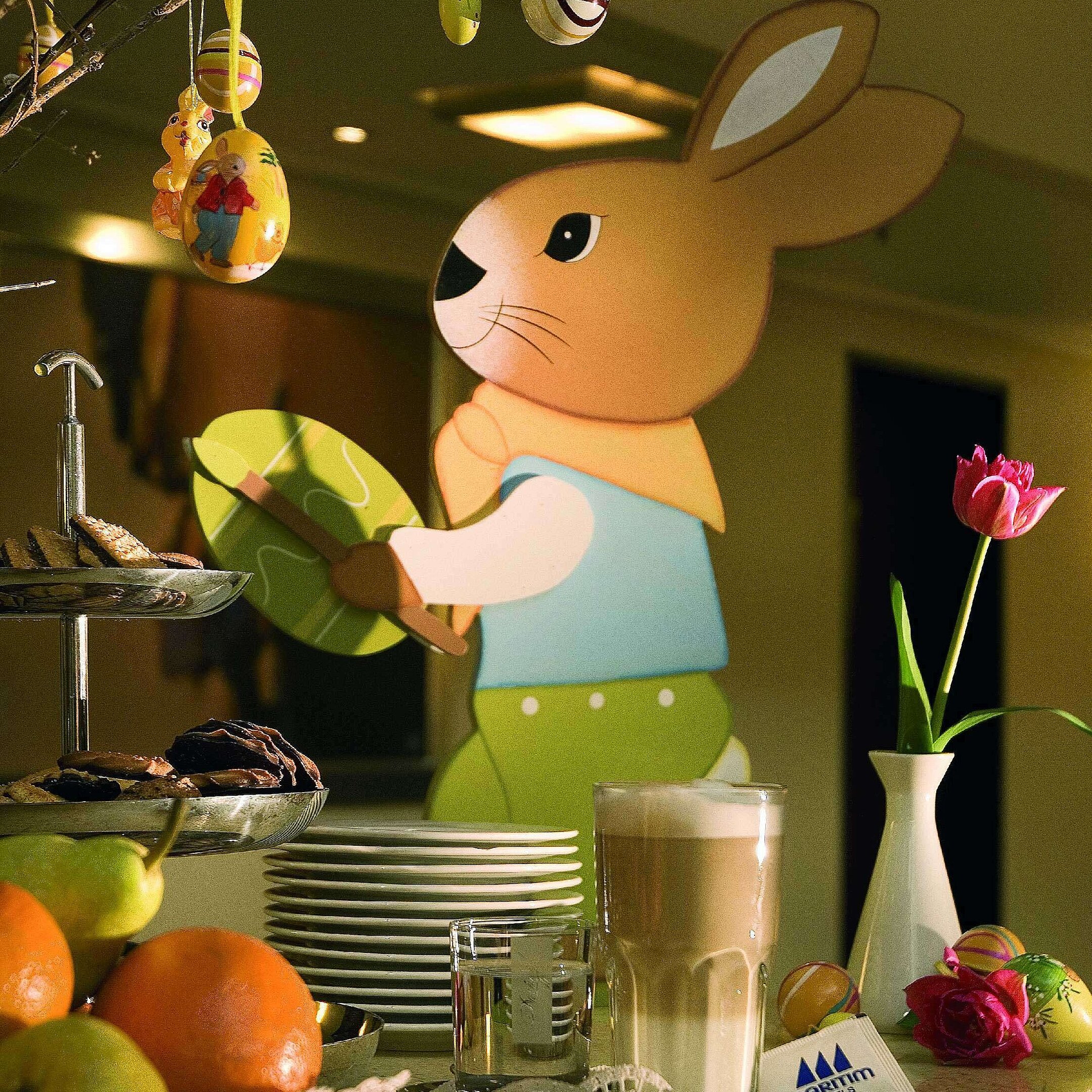 Festively decorated table with Easter bunny, colorful eggs, and latte macchiato at Maritim Hotel Fulda.