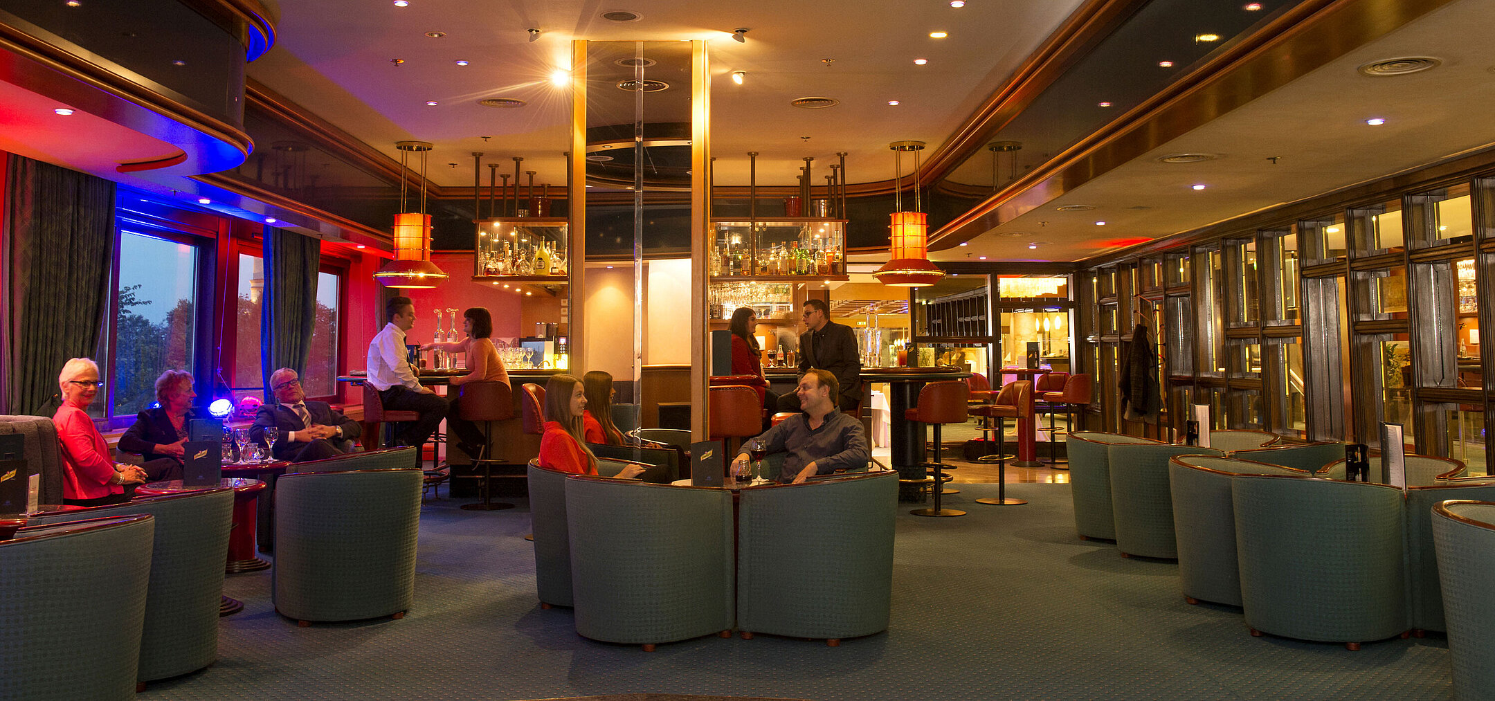 Ospiti si godono drink e conversazioni nel bar del Maritim Hotel Travemünde la sera
