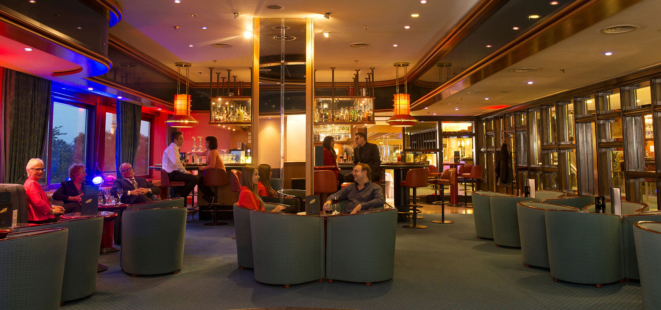 Clients savourent des boissons et échangent à la bar du Maritim Hotel Travemünde en soirée