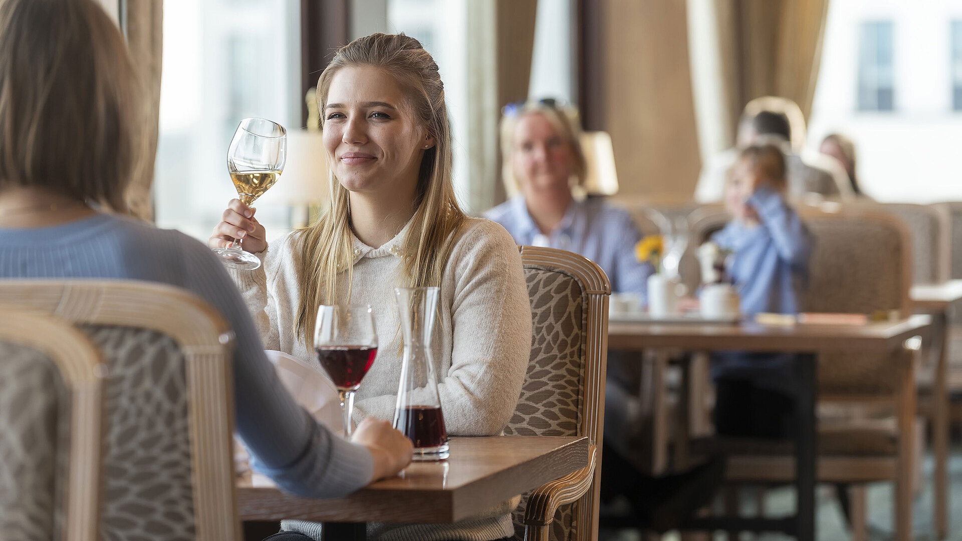 Woman with white wine enjoying the elegant restaurant atmosphere at Maritim Hotel Travemünde