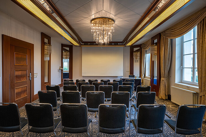 Elegant event room at a Maritim hotel with theatre seating and presentation screen.