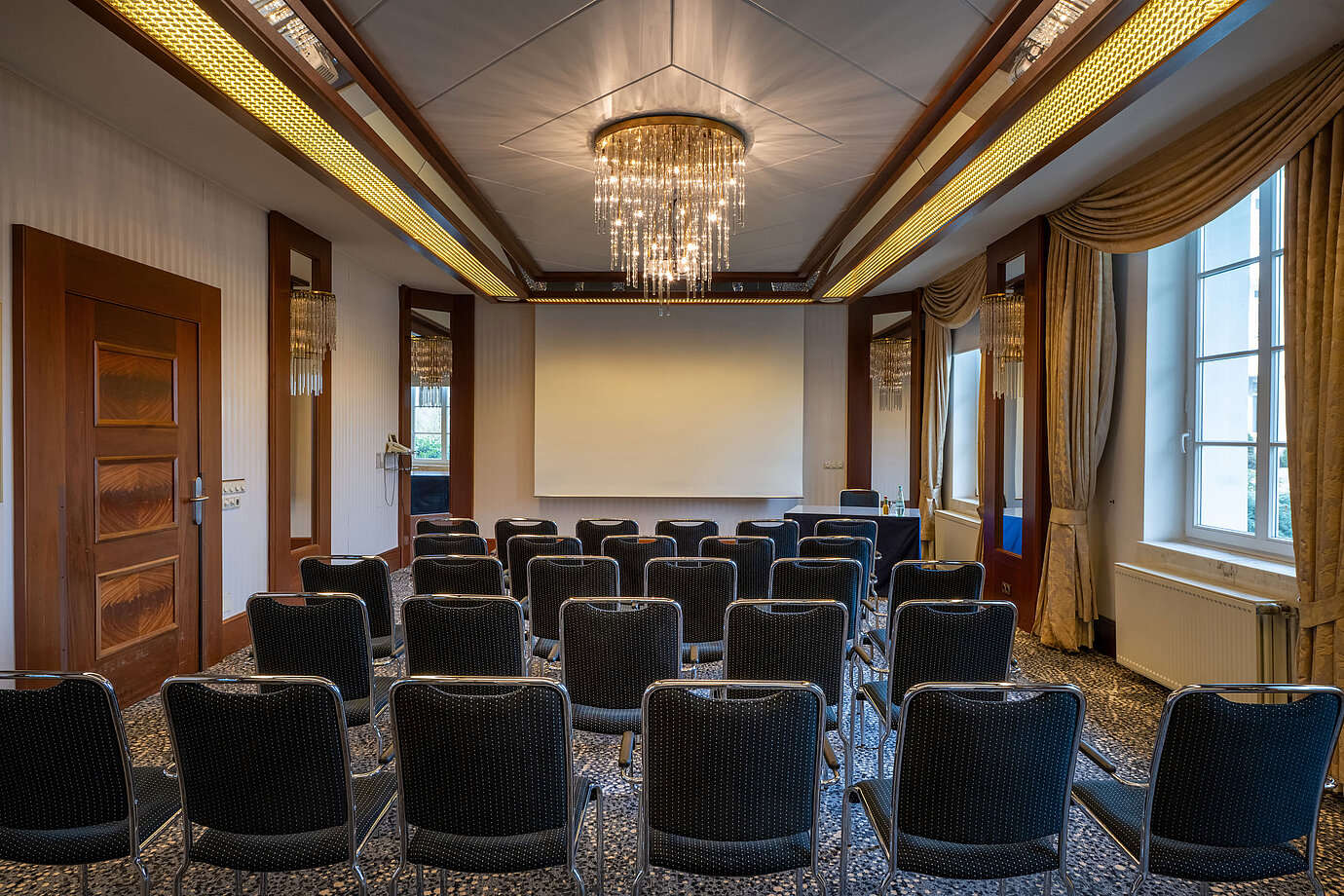 Elegant event room at a Maritim hotel with theatre seating and presentation screen.