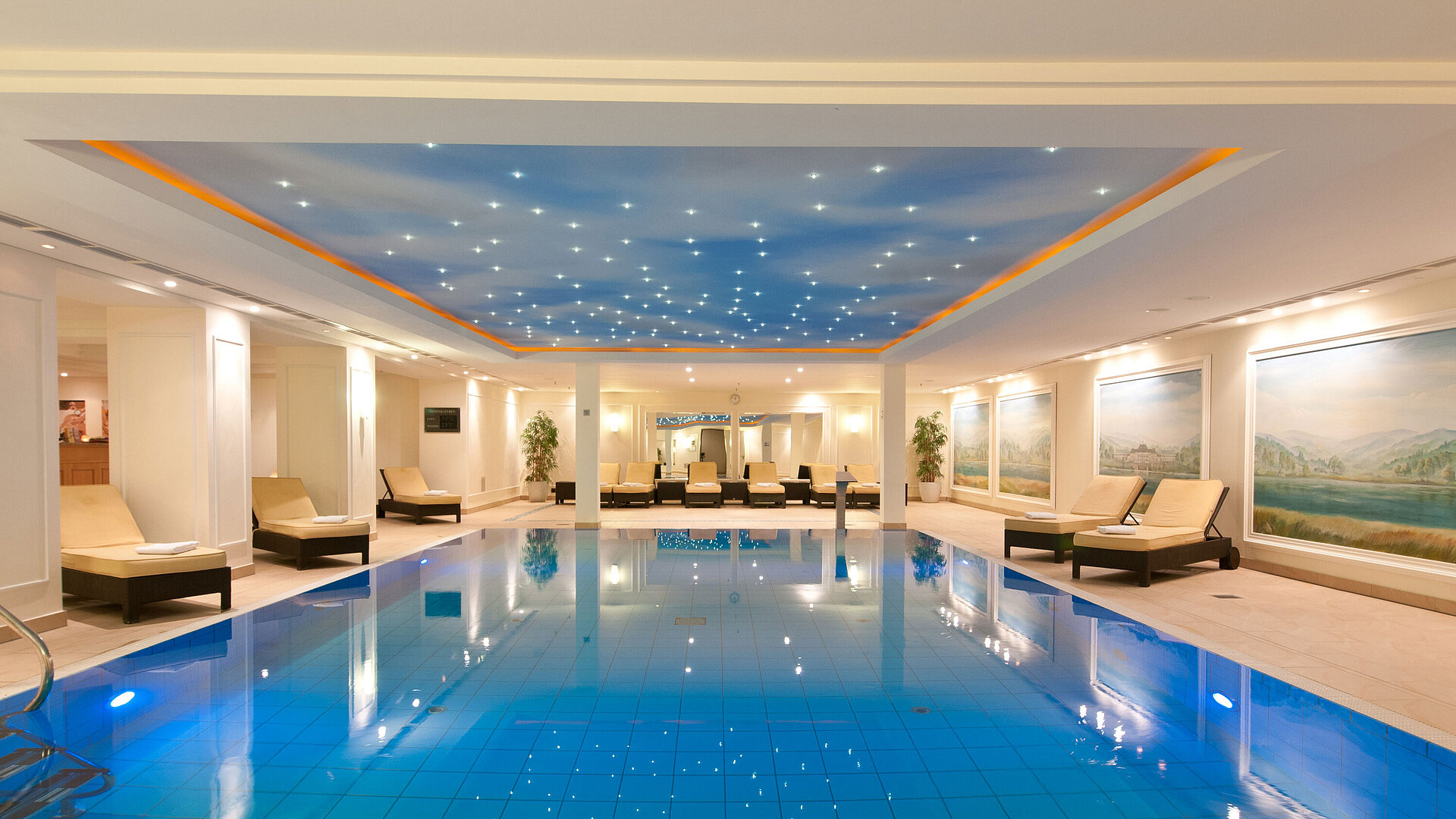 Piscina cubierta lujosa en el Maritim Hotel Dresden con tumbonas y iluminación ambiental en el techo.