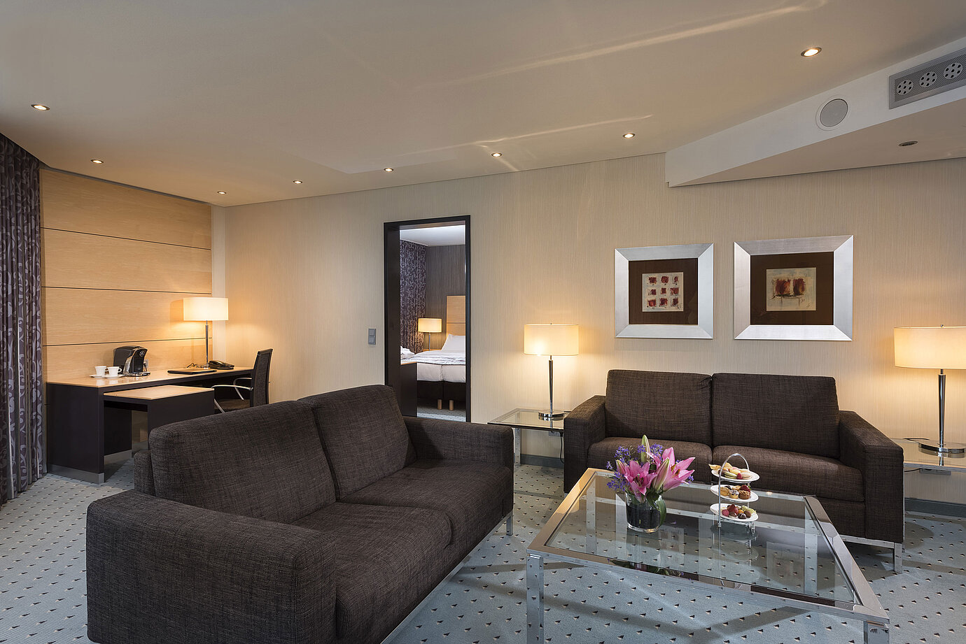 Suite Junior à l’hôtel Maritim Düsseldorf avec salon séparé, deux canapés, bureau, fleurs et design moderne.