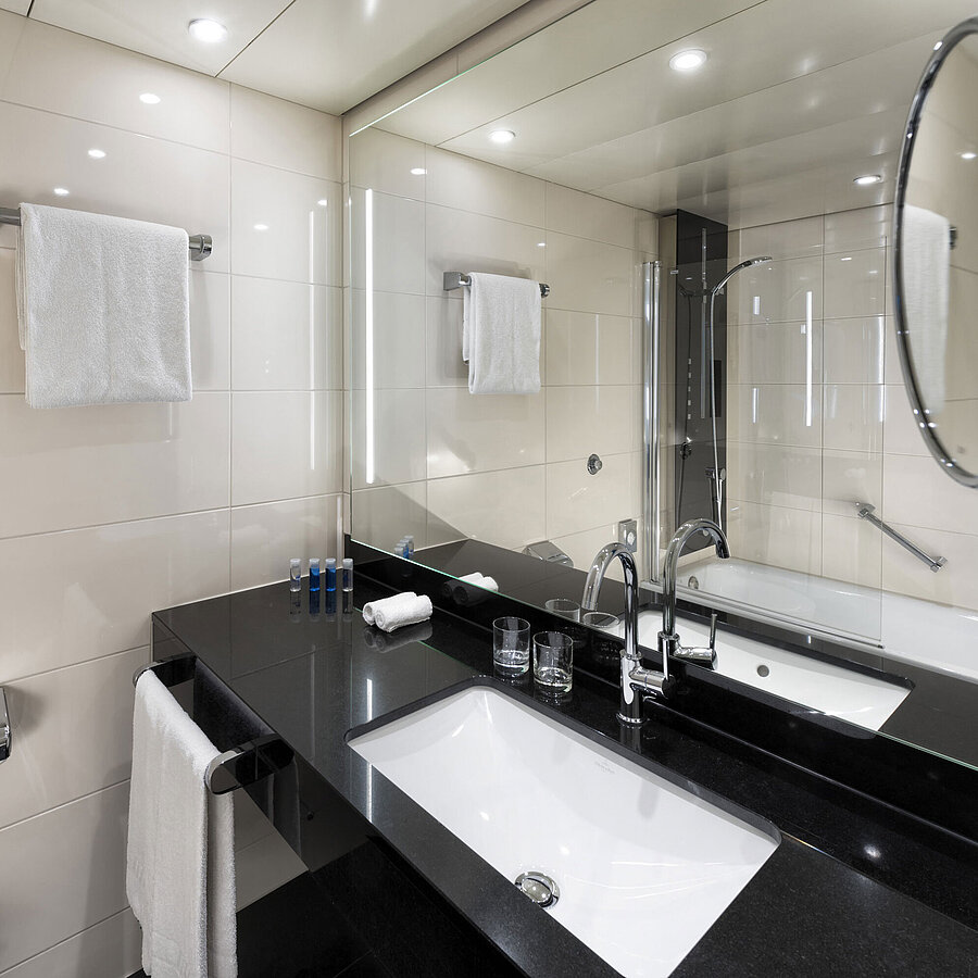 Modern bathroom at Maritim Hotel Ulm with a bathtub and stylish lighting.