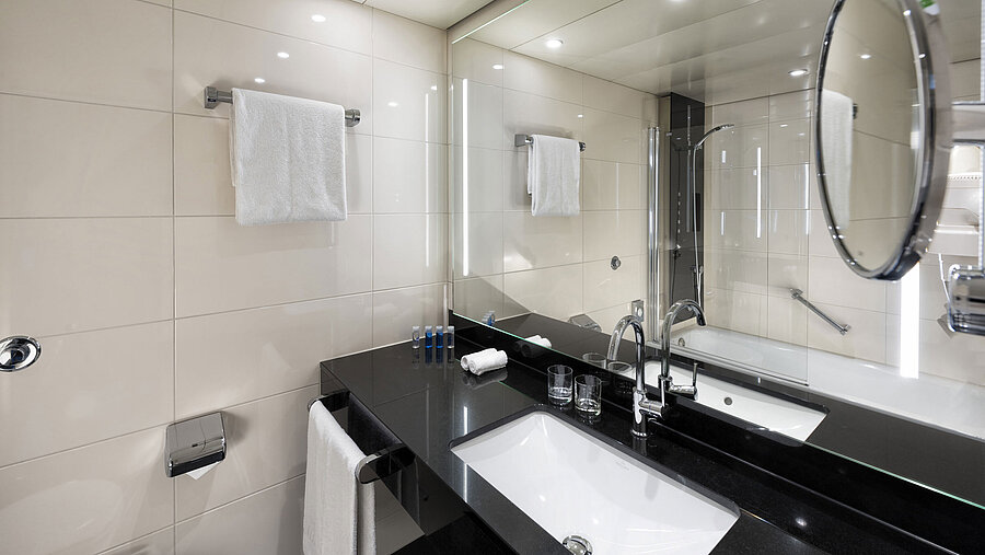 Baño moderno en el Maritim Hotel Ulm con bañera e iluminación elegante.
