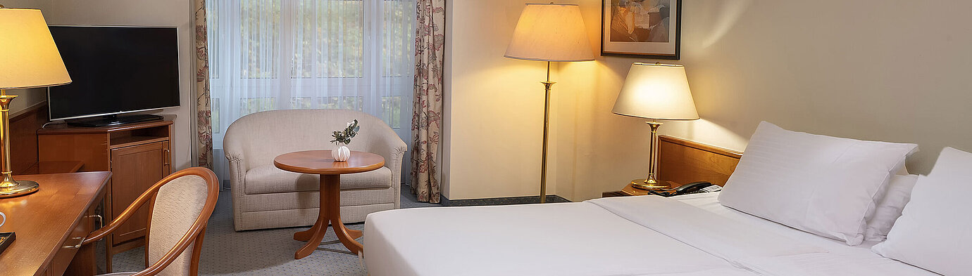 Classic room Classic room with double bed, desk, TV, seating area and large window in a bright interior design.