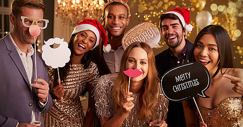 © Monkey Business - AdobeStock.com Grupo elegante celebrando fiesta de Navidad con vino espumoso y gorros de Santa