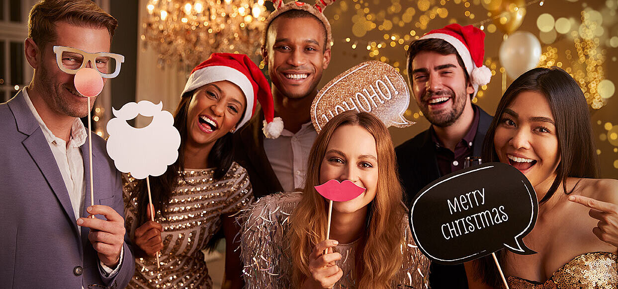 © Monkey Business - AdobeStock.com Elegant group celebrating Christmas party with sparkling wine and Santa hats in golden setting