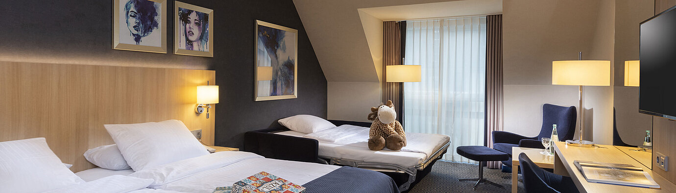 Camera Familiare Comfort al Maritim Hotel Würzburg con divano letto, letto matrimoniale e peluche
