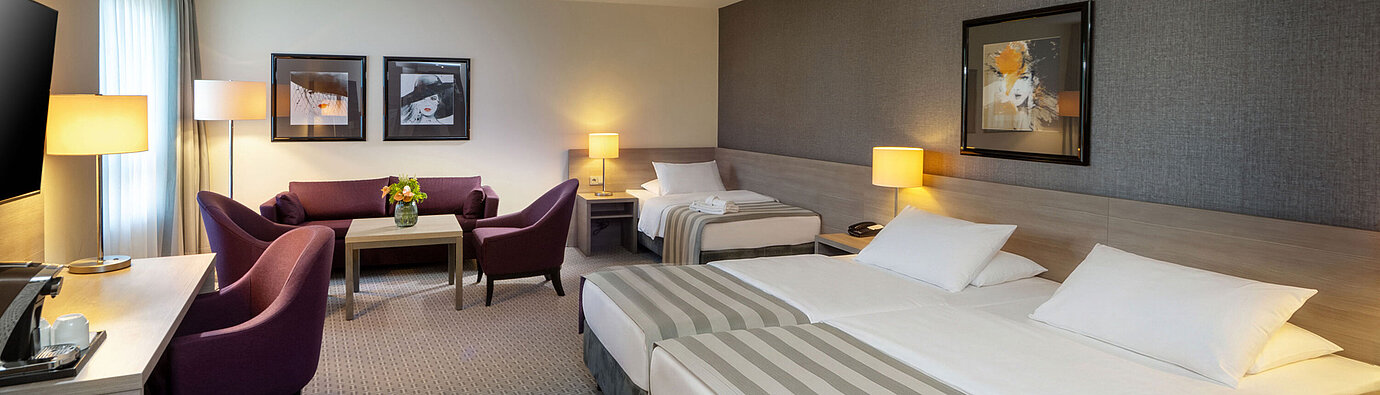 Habitación familiar Classic Habitación familiar Classic del Maritim Hotel Königswinter con cama doble, sofá cama y zona de estar.