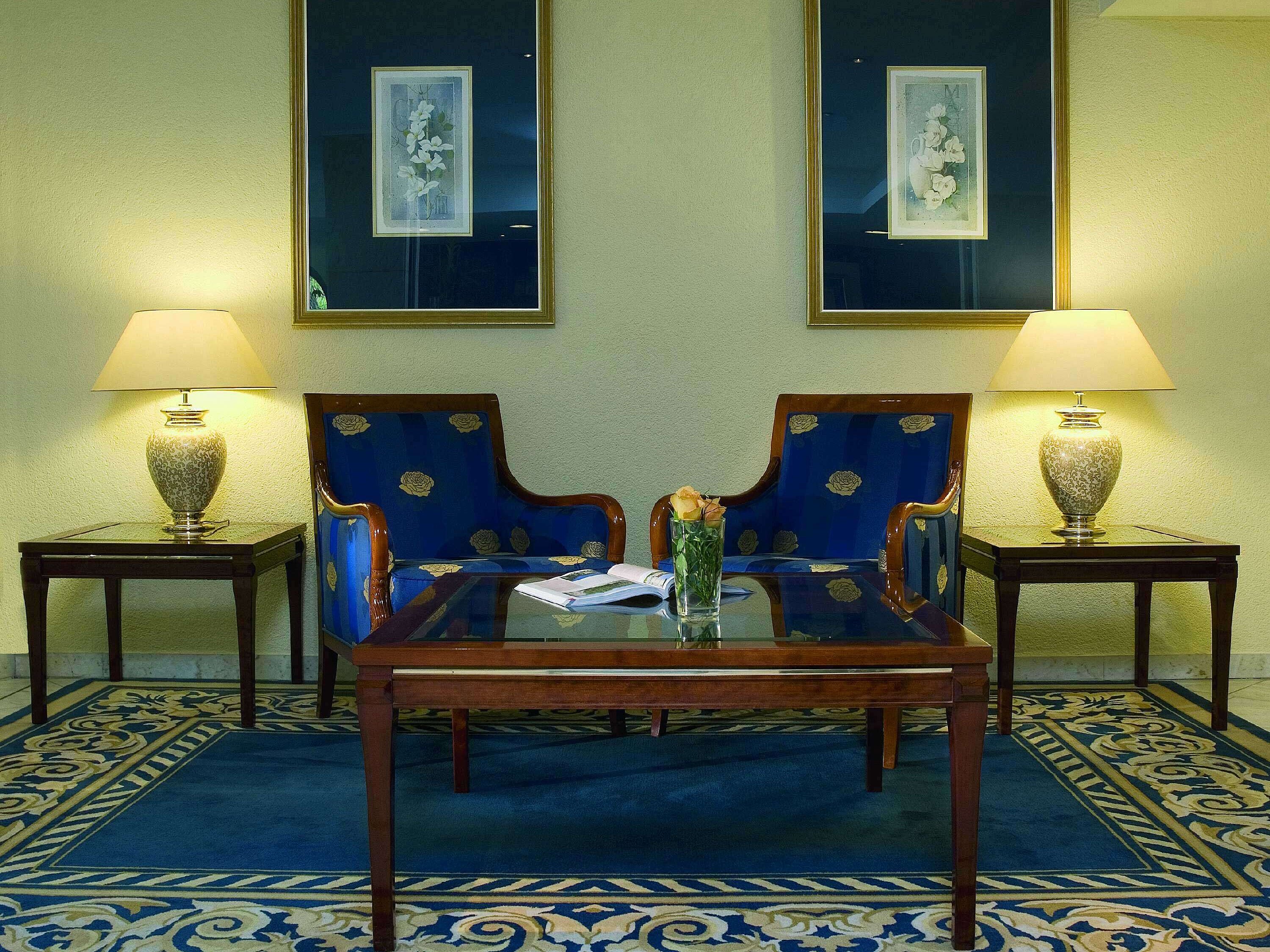 Elegante vestíbulo del Maritim Hotel Fulda con sillones azules, mesa de vidrio y luz ambiental.