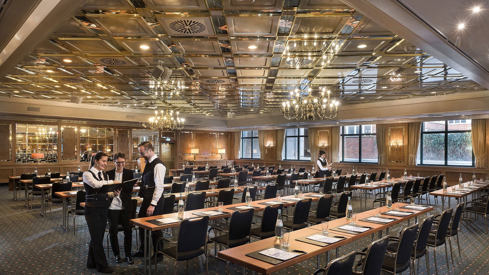 Dos empleados preparan sala de reuniones con sillas en fila en el Maritim Hotel Stuttgart
