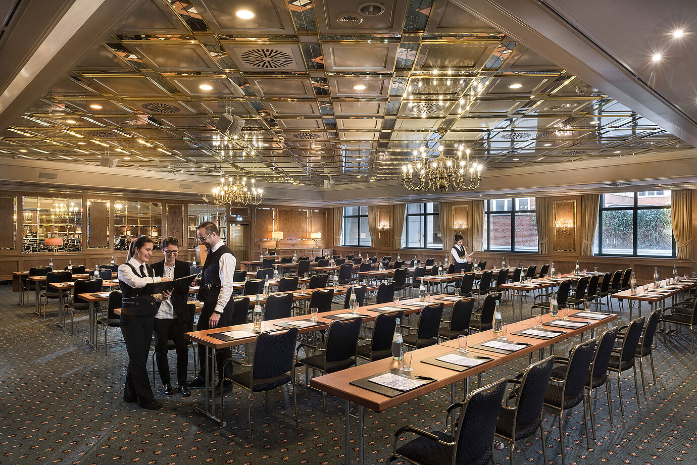 Dos empleados preparan sala de reuniones con sillas en fila en el Maritim Hotel Stuttgart