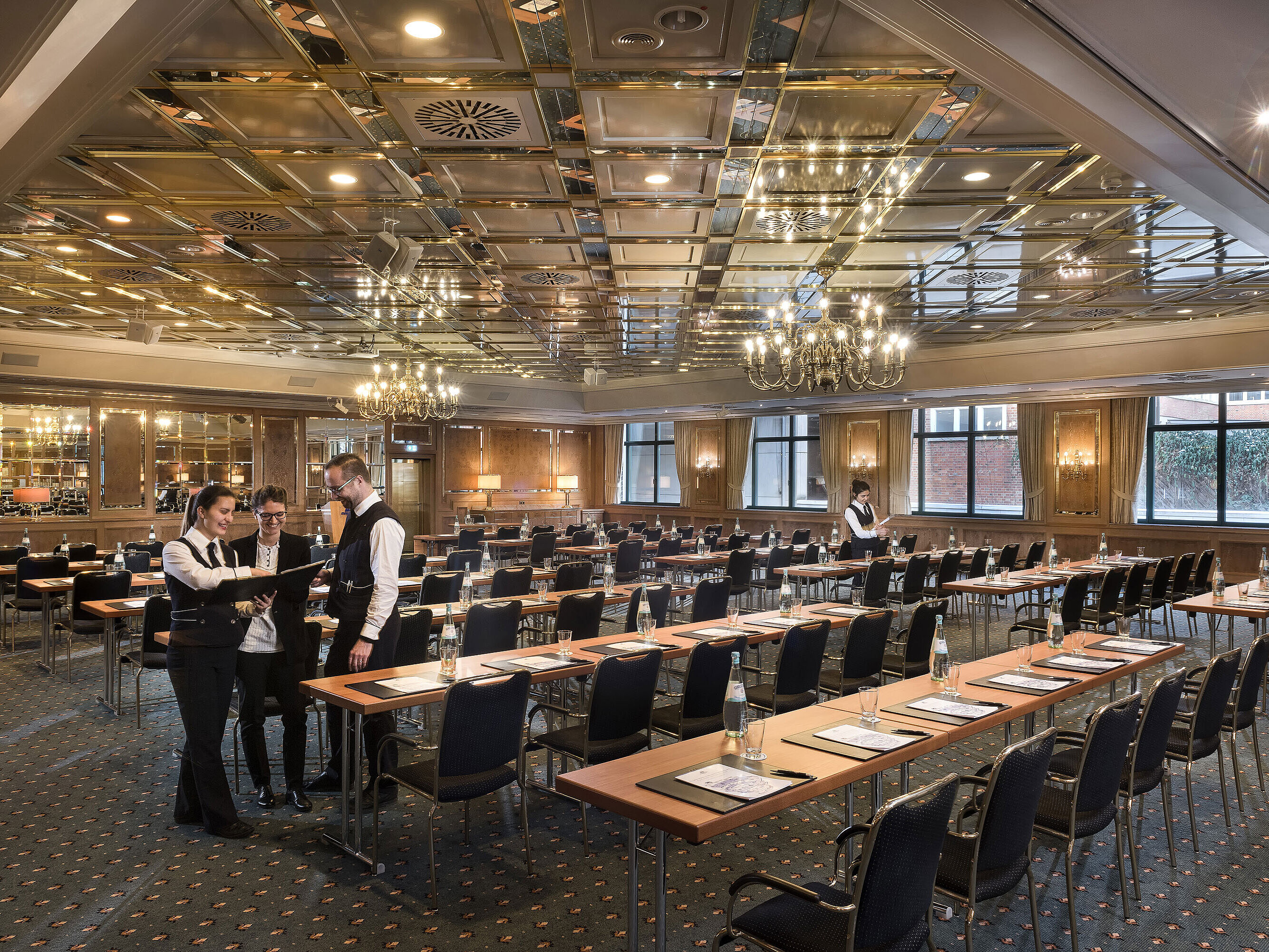 Dos empleados preparan sala de reuniones con sillas en fila en el Maritim Hotel Stuttgart