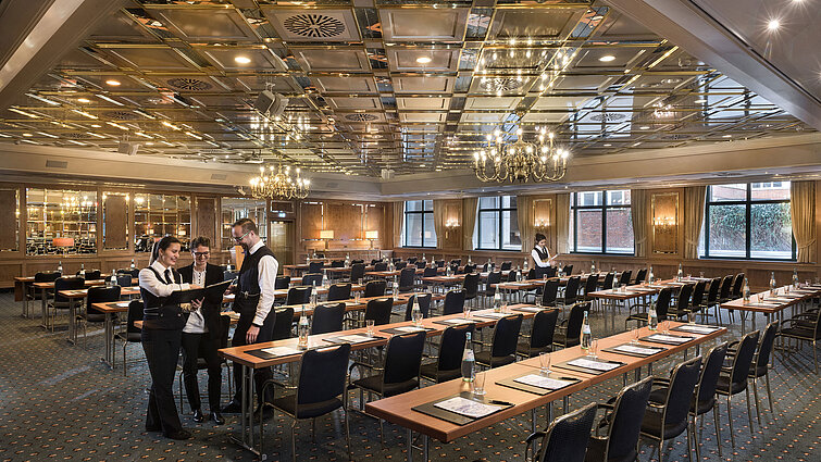Deux employés préparent une salle de conférence avec chaises en rangée au Maritim Hotel Stuttgart