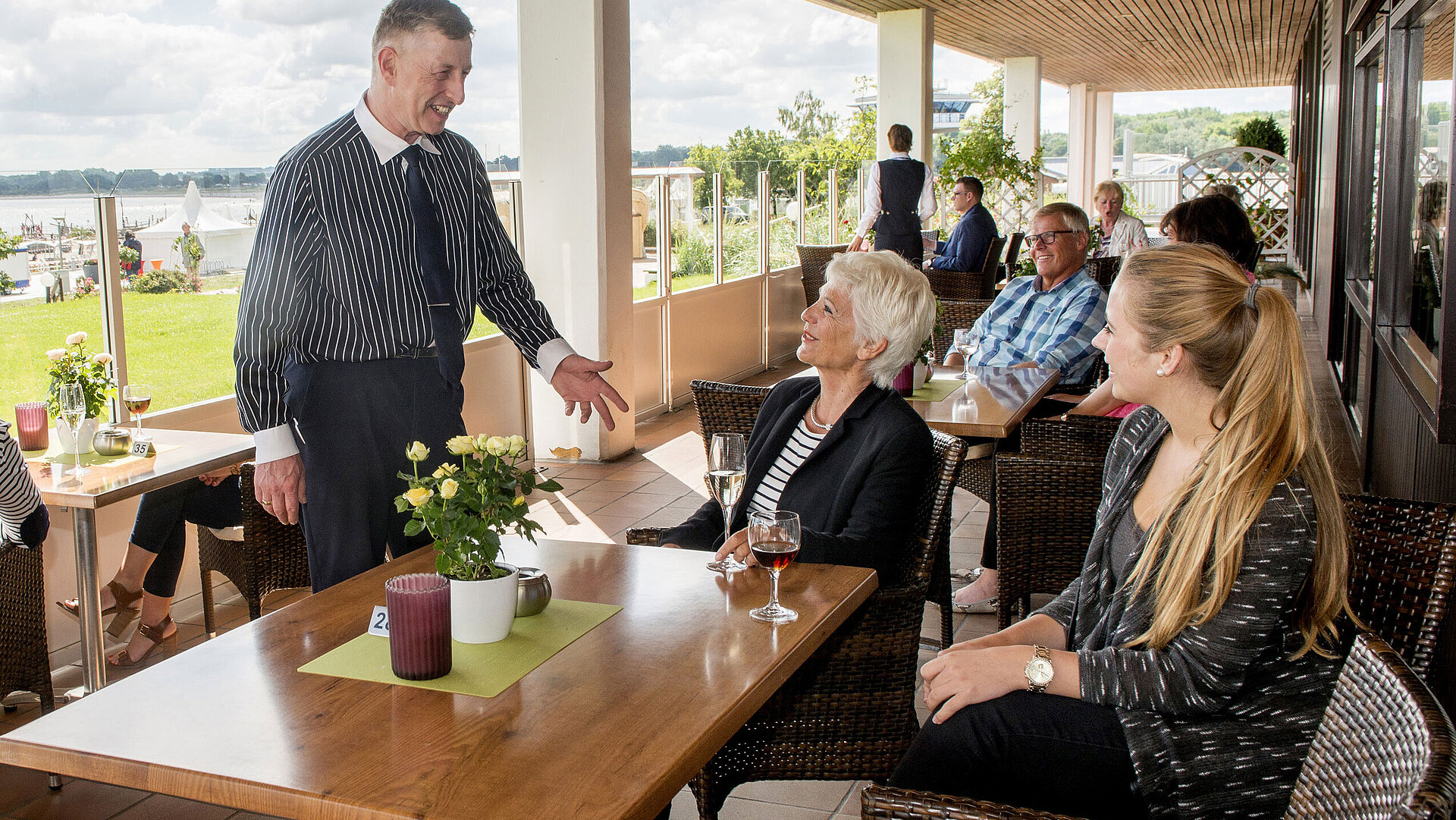 Clients profitent de boissons et de conversations sur la terrasse avec vue sur la mer Baltique.
