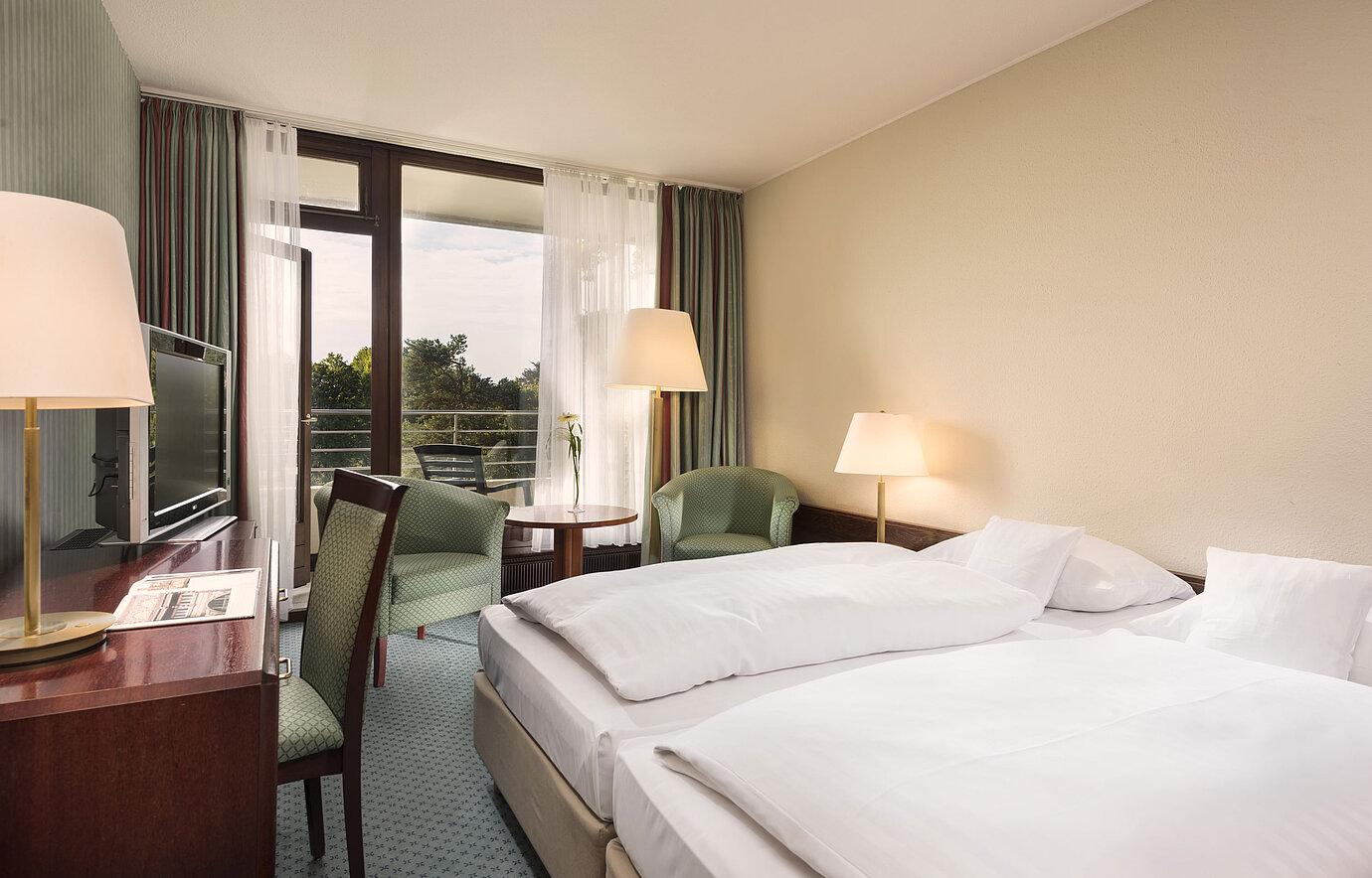 Chambre avec balcon, fauteuils et bureau à l’hôtel Maritim Bad Salzuflen