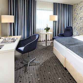 Habitación Superior en el Hotel Maritim Bonn con diseño moderno, cama acogedora, escritorio y cortinas elegantes. 