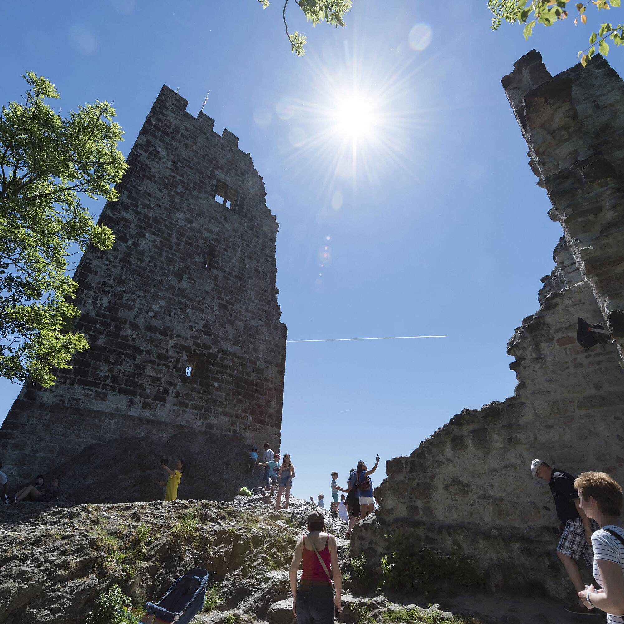 The historic Drachenfels castle ruins in Königswinter with visitors and bright sunshine.