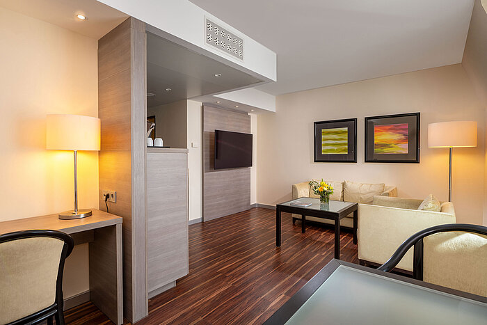 Suite Junior Suite Junior del Maritim Hotel Königswinter con sala de estar, zona de asientos, escritorio y distribución abierta.