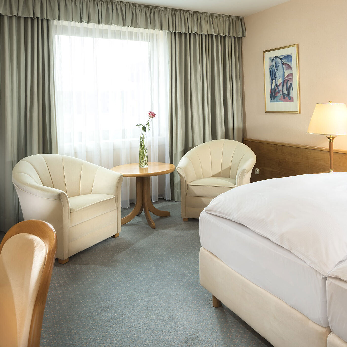 Habitación luminosa con dos camas, zona de estar y ventana grande en el Maritim Hotel Magdeburg