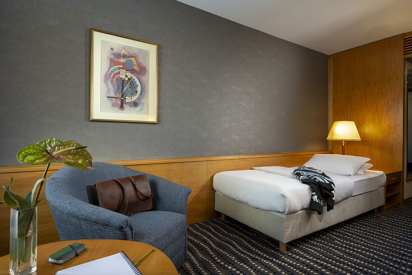 Chambre simple classique avec bureau, lampe de chevet et décoration murale moderne