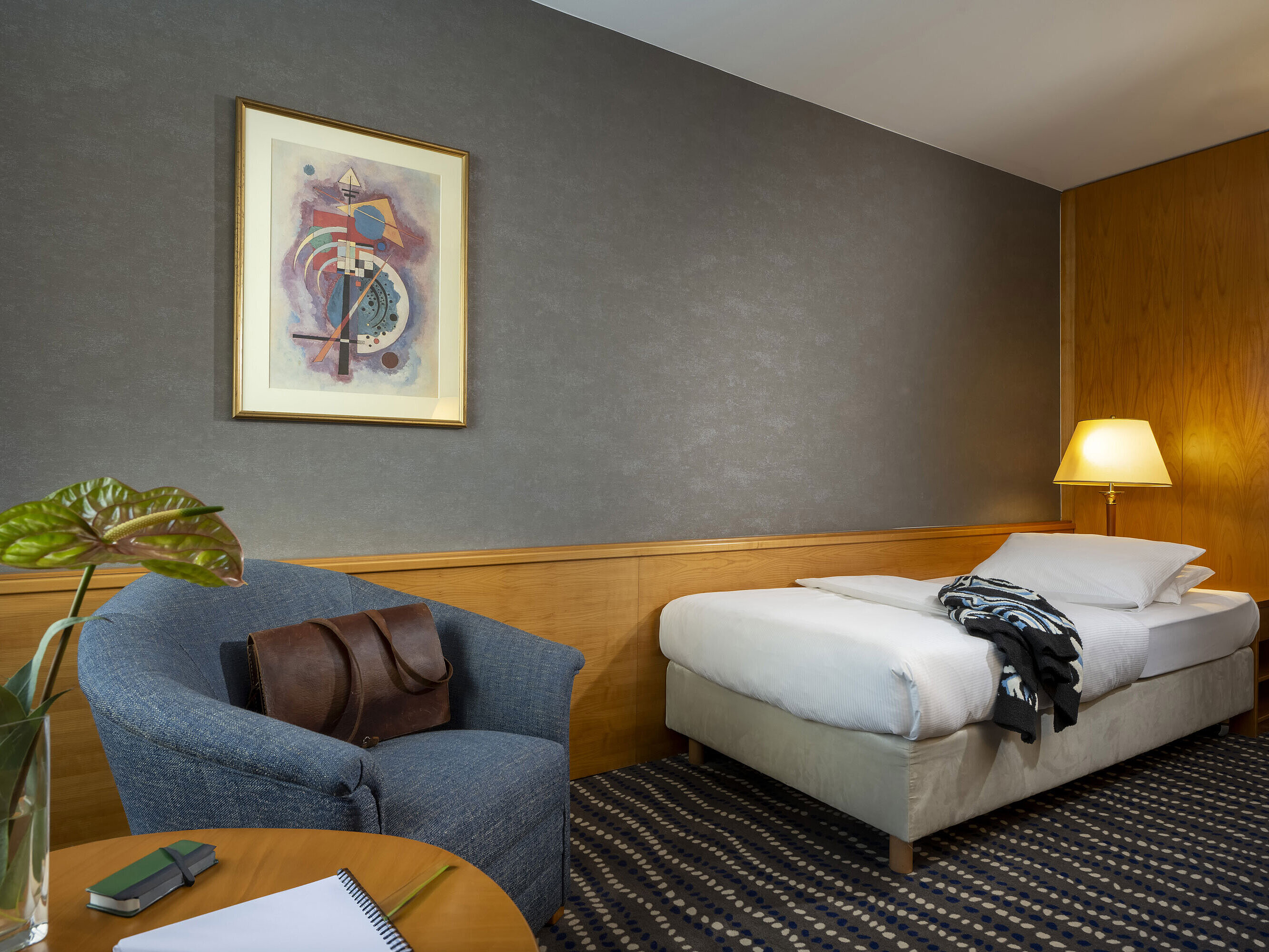 Classic single room with desk, bedside lamp, and modern wall art