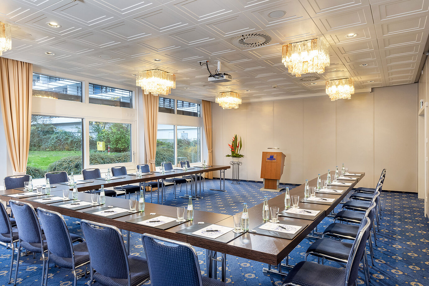 El Salón Lübeck del Maritim Hotel Kiel, una moderna sala de conferencias con asientos en forma de U, grandes ventanales y lámparas de araña.
