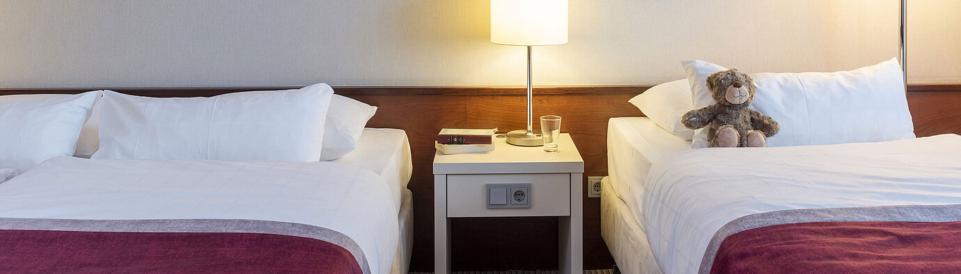 Classic Family room  Classic family room at Maritim Hotel Bonn with two beds, bedside table, and modern art for a comfortable stay.