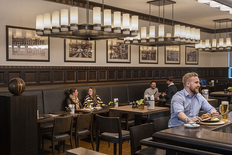Guests enjoying meals in the cozy "Rheinische Stov" restaurant at Maritim Hotel Düsseldorf with stylish interior and ambiance