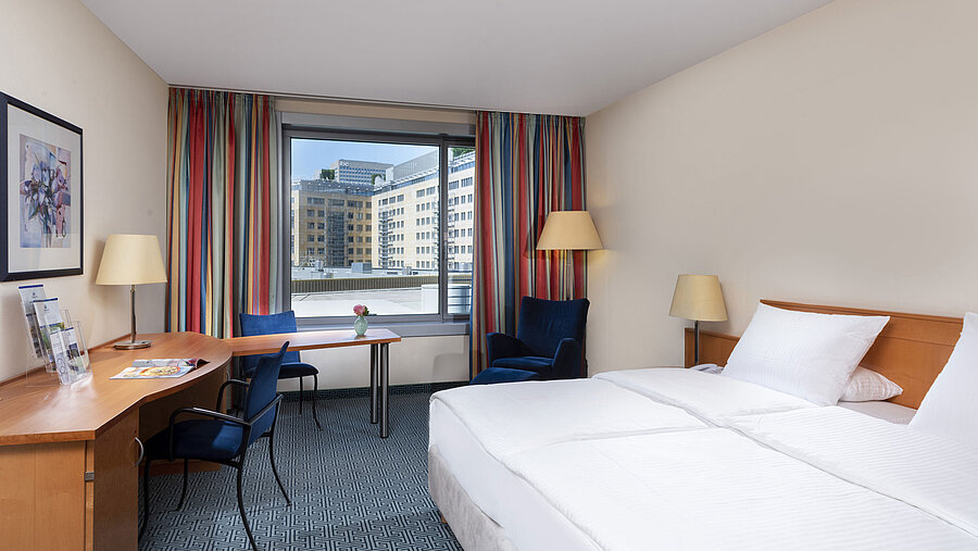 Chambre Classic du Maritim Hotel Frankfurt avec lit double confortable, bureau et vue sur la ville.