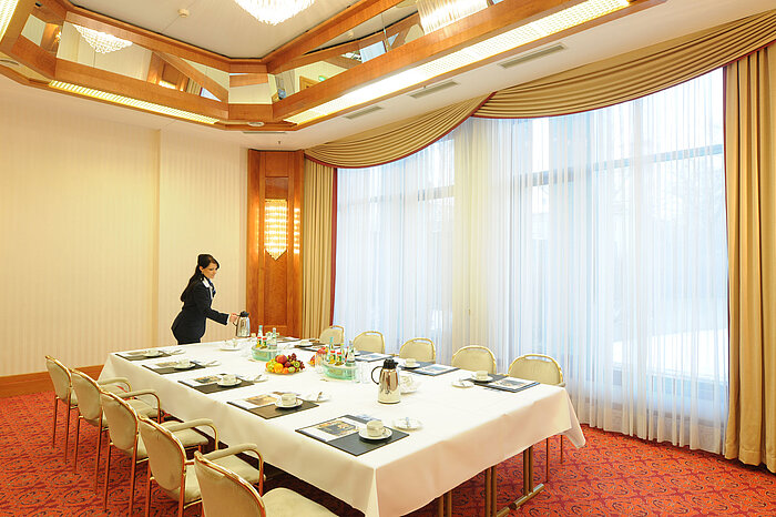 Sala de reuniones elegante con luz natural, mesa preparada y ambiente cálido en el Maritim Hotel Magdeburg.