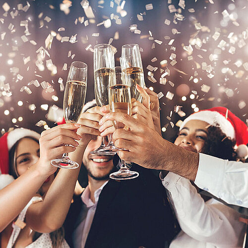 © Prostock-studio - AdobeStock.com People clinking glasses of sparkling wine at a festive Christmas party – joyful mood in a cosy, festive setting