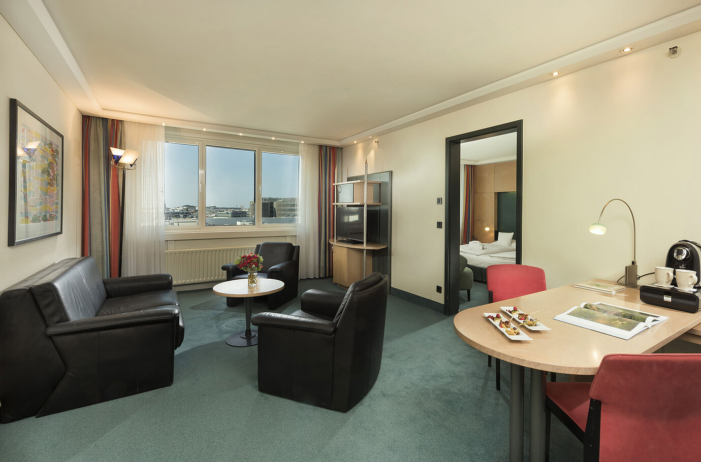 Salon de la Suite Supérieure de l’hôtel Maritim proArte Berlin avec coin salon et vue par la fenêtre.