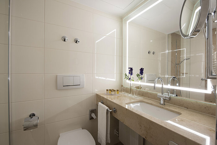 Bright bathroom with large mirror and amenities at Maritim Hotel Titisee