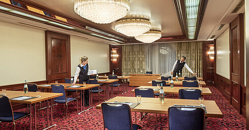 Salón Bonn en Maritim Colonia, el personal prepara la sala con mesas, botellas de agua y vasos para un evento.