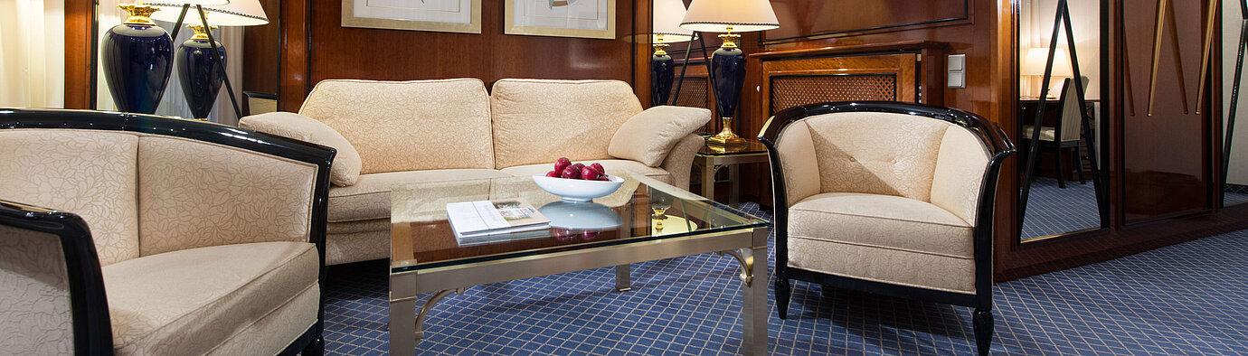 Salon élégant d’une suite au Maritim Hotel Fulda avec mobilier raffiné, table basse en verre et éclairage chaleureux.