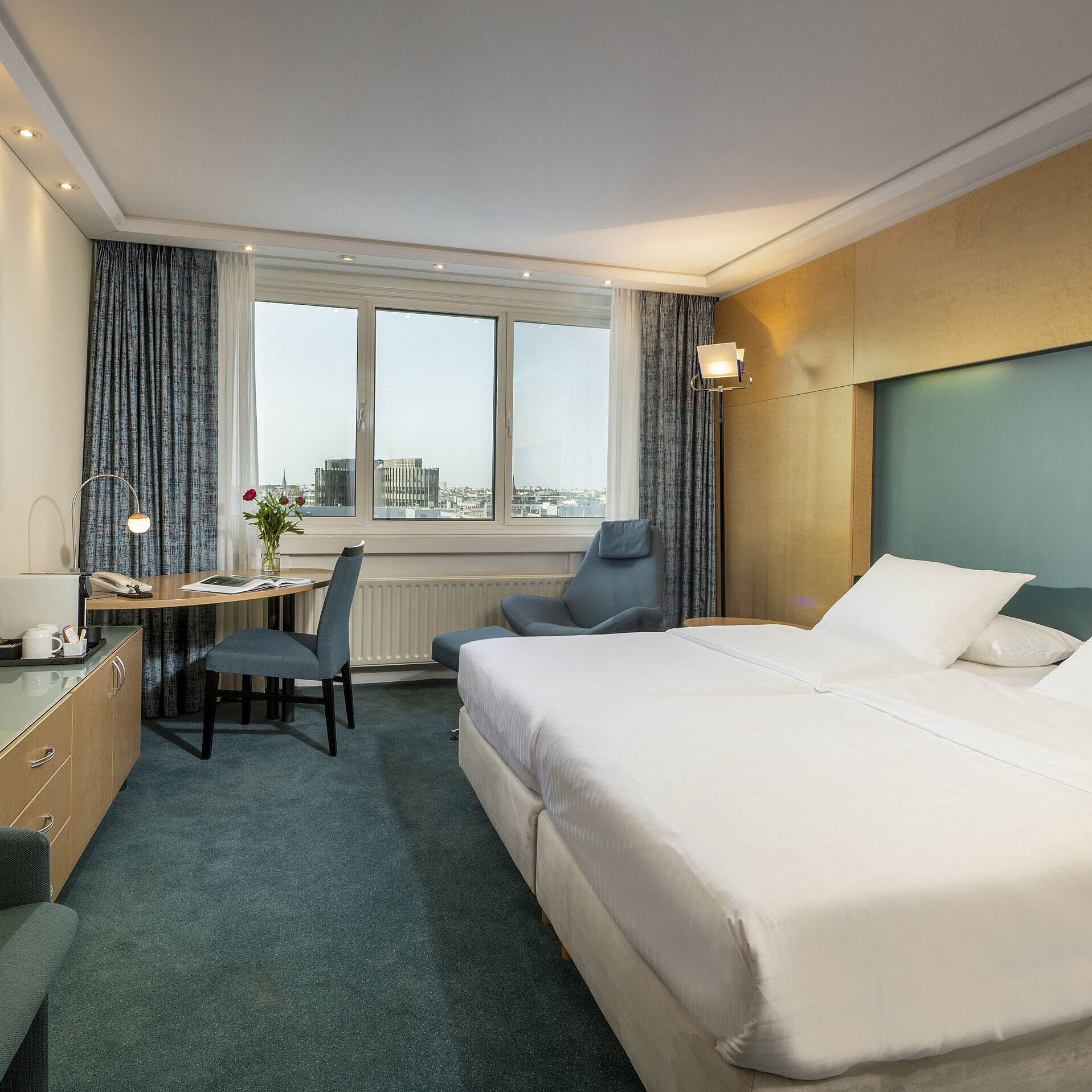 Habitación Superior modernamente amueblada en el hotel Maritim con cama grande, escritorio, obra de arte y vista a la ciudad.