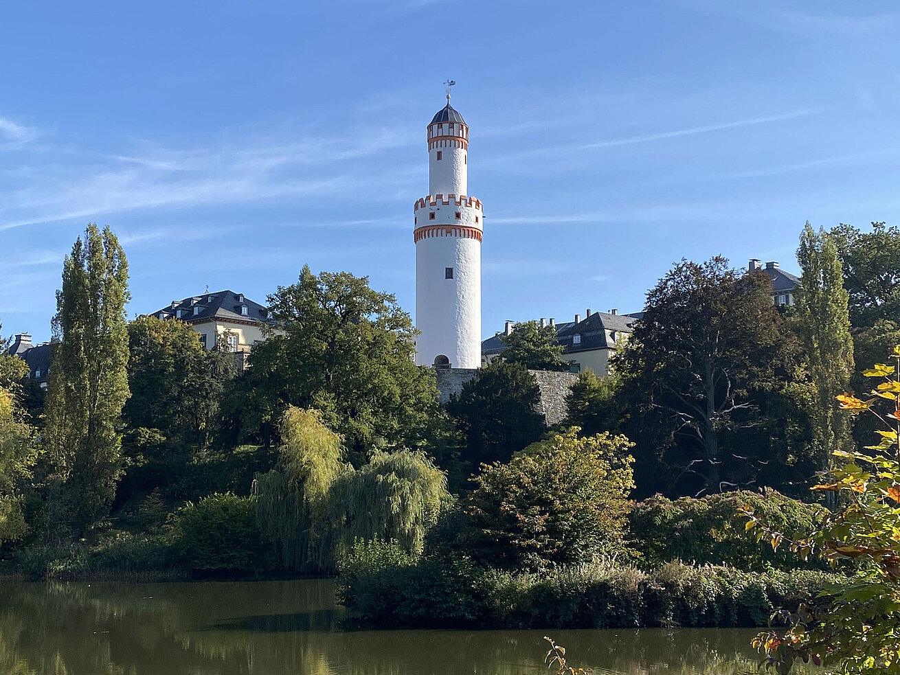 Castello di Bad Homburg Torre bianca a Bad Homburg con cielo azzurro e circondata da natura verde.