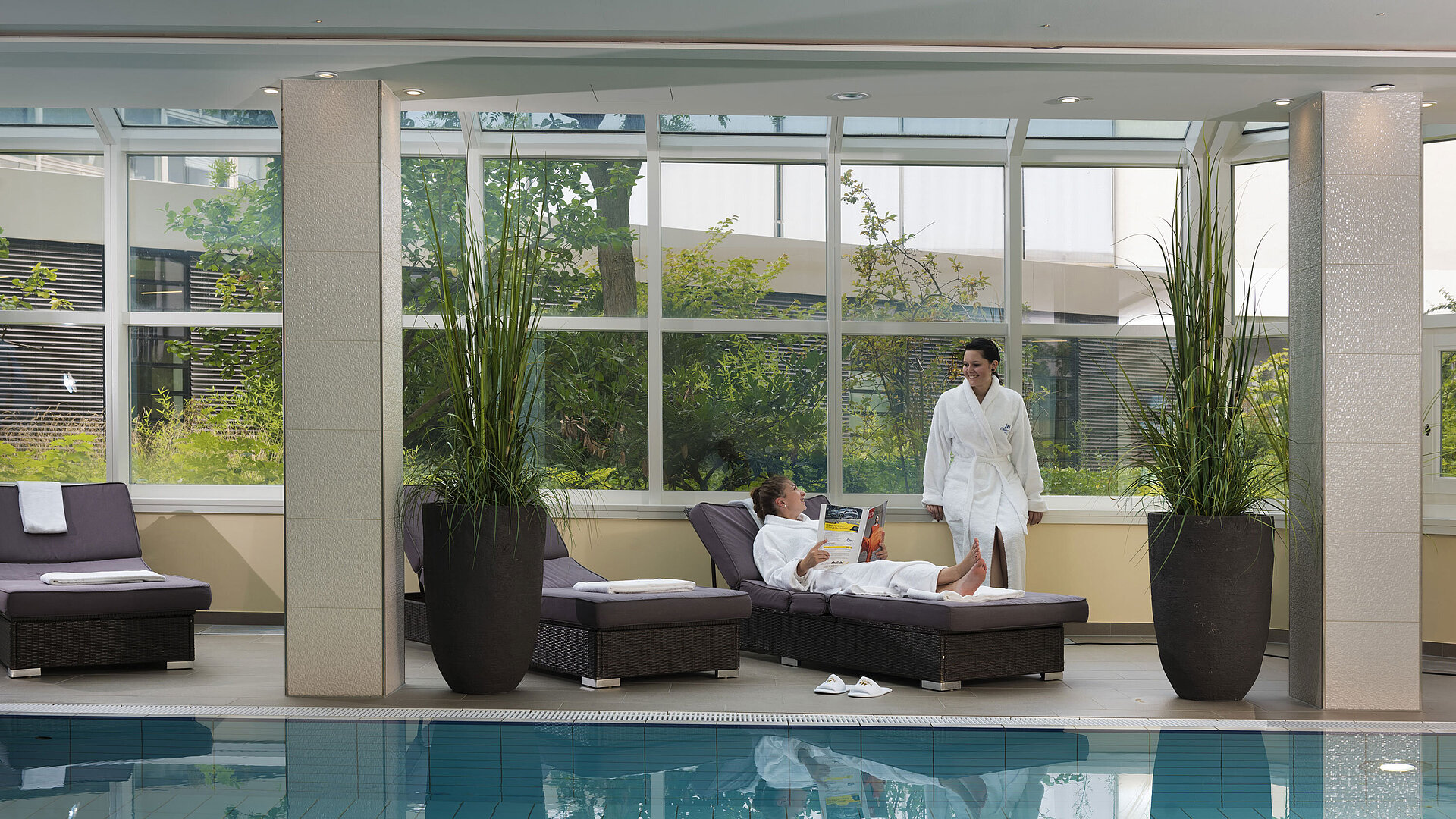 Espace bien-être avec piscine et chaises longues au Maritim Hotel Würzburg – invités en peignoirs.