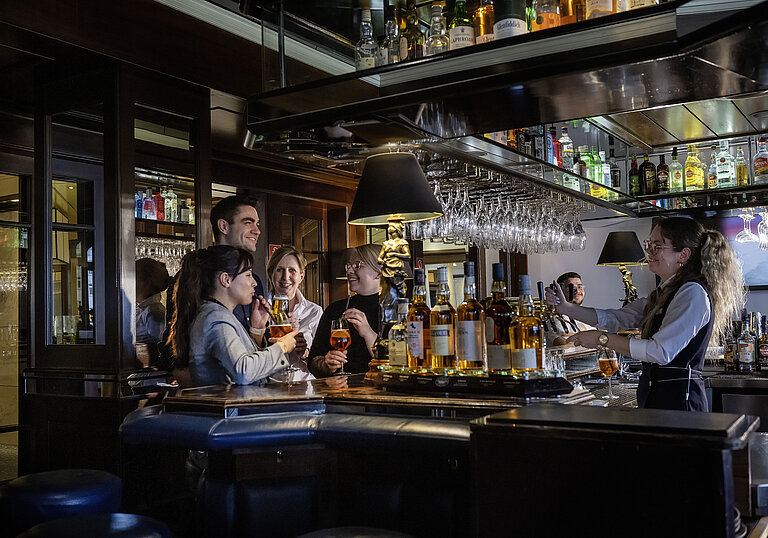 Guests enjoying cocktails and great vibes at the bar of Maritim Hotel Darmstadt. Friendly bar staff serving drinks.