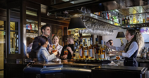 Des clients profitent de cocktails et d'une ambiance chaleureuse au bar de l'hôtel Maritim Darmstadt.
