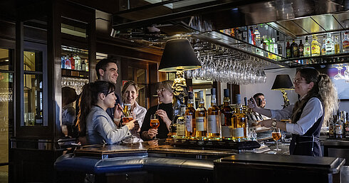 Guests enjoying cocktails and great vibes at the bar of Maritim Hotel Darmstadt. Friendly bar staff serving drinks.