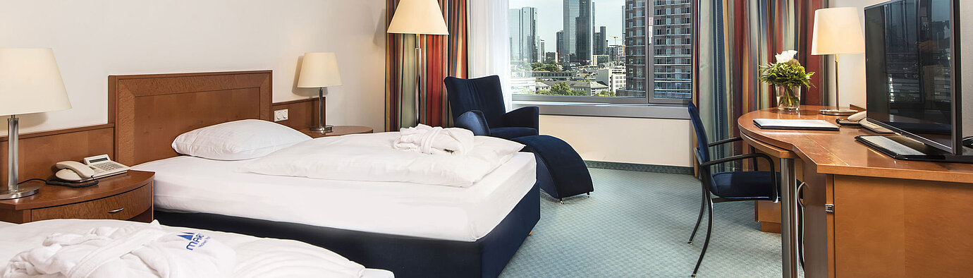 Chambre supérieure à l'hôtel Maritim Frankfurt avec deux lits simples, bureau, coin salon et vue imprenable sur la skyline.