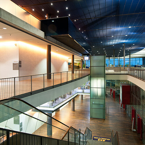 Atrio moderno e iluminado del Maritim Hotel Dresde con escaleras mecánicas y arquitectura de vidrio.