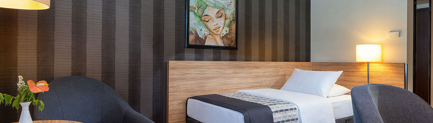 Habitación individual Classic Habitación individual Classic del Maritim Hotel Königswinter con cama individual, zona de estar y ambiente moderno.