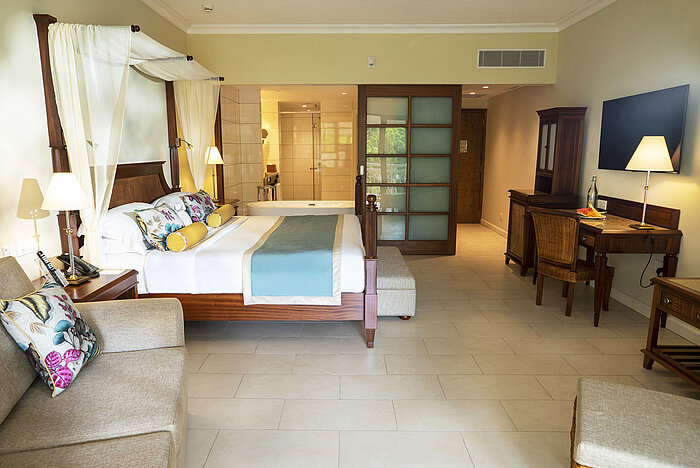 Amplia habitación con cama doble, escritorio y baño abierto en el Maritim Hotel