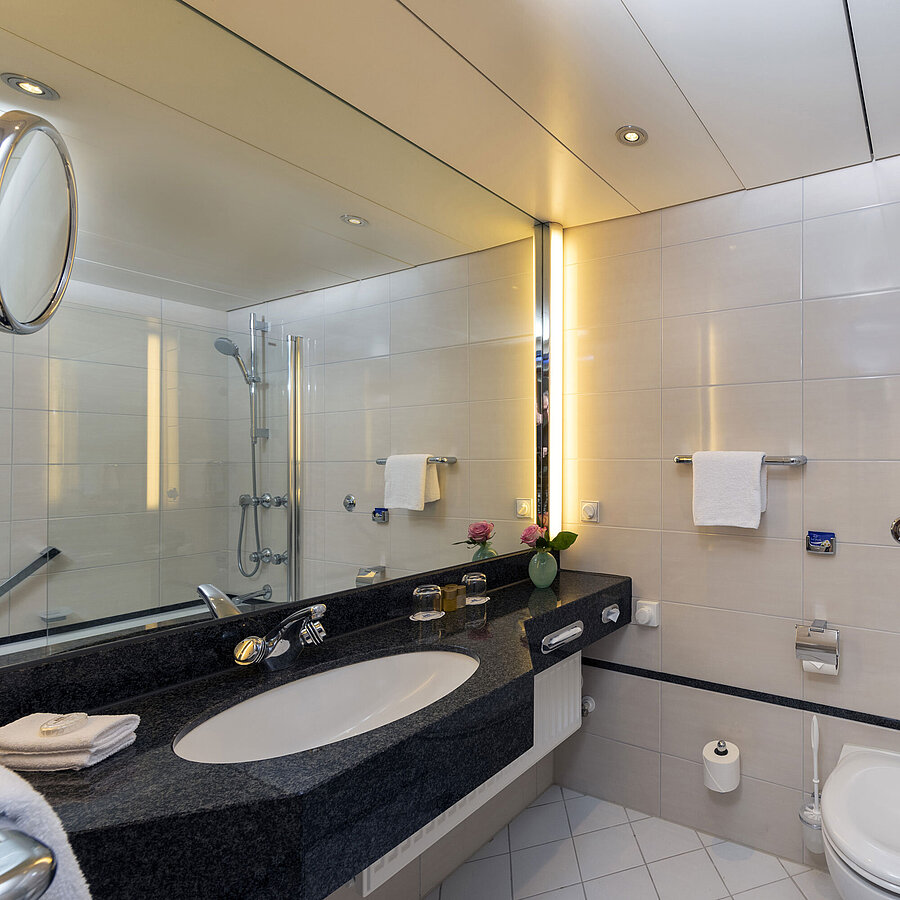 Modern bathroom at Maritim Hotel Frankfurt with large mirror, stylish sink, and shower-bathtub.