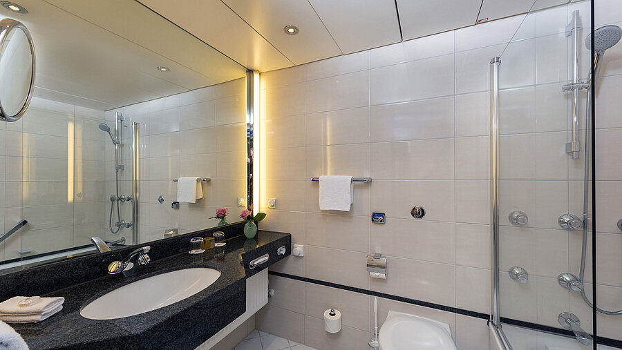 Salle de bain moderne du Maritim Hotel Frankfurt avec grand miroir, lavabo élégant et baignoire-douche.